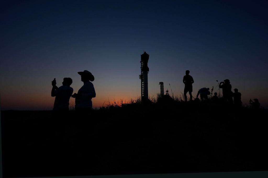 Menschen fotografieren den Sonnenuntergang hinter der Rakete Starship von SpaceX.