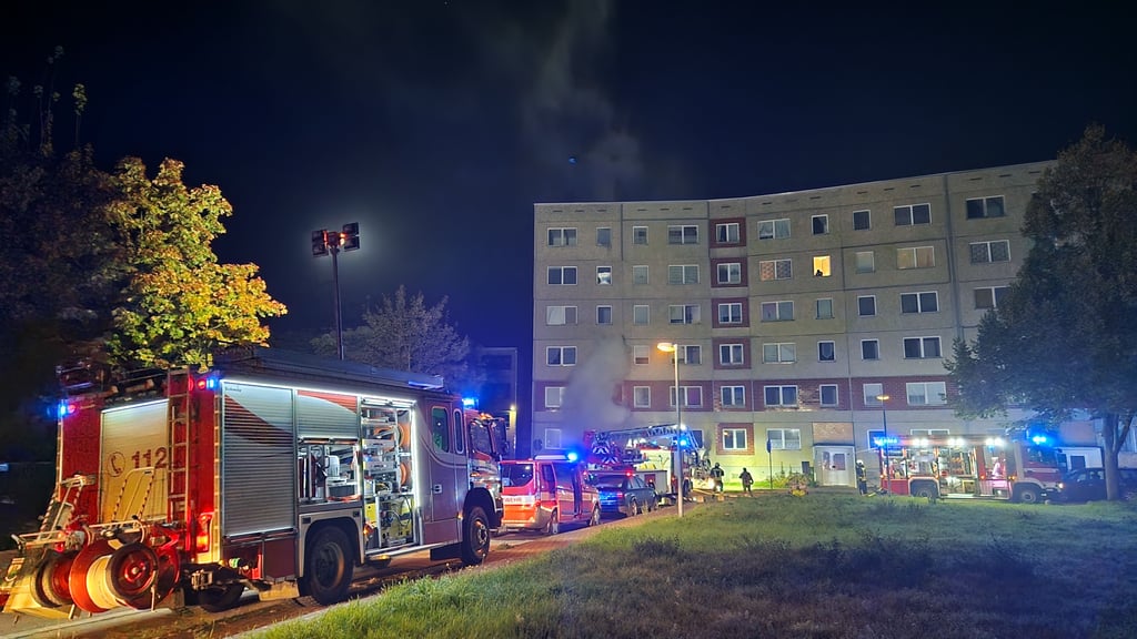 Feuerwehreinsatz im Aalweg in Halle: Im Hintergrund sind bereits dichte Rauchschwaden in dem brennenden Plattenbau in Heide-Nord zu erkennen..