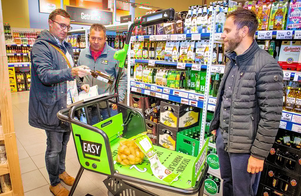 Tageblatt/MZ-Redakteur Harald Boltze (v.l.) scannt unter den Augen von Inhaber Daniel Hinze und Edeka-IT-Trainer Benjamin Schulze eine Bierflasche. Die Kartoffeln waren schon zuvor in dem neuen digitalen Wagen gelandet.