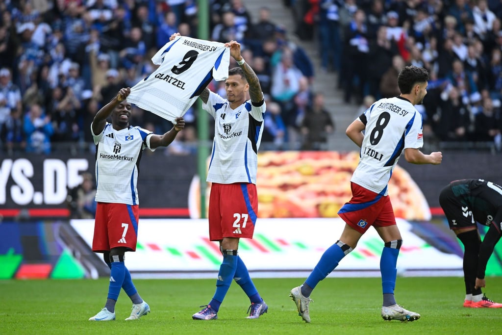 Gruß an Glatzel: Die HSV-Spieler Davie Selke (M) und Jean-Luc Dompe jubeln mit einem Trikot ihres verletzten Torjägers.