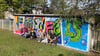  Lehrer Dirk Marstalerz (links), die Achtklässler und Projektleiter Tim Heidler (rechts) sind stolz auf ihr Graffiti an der Garage am Sportplatz in Weißenfels West. 