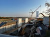 Die Baugrube liegt unterhalb der blauen Fußgängebrücke bei Schiepzig. Im Vordergrund ist ein Teil der Brücke samt Mittelwand. Im Hintergrund führt die Abfahrt nach Salzmünde lang.