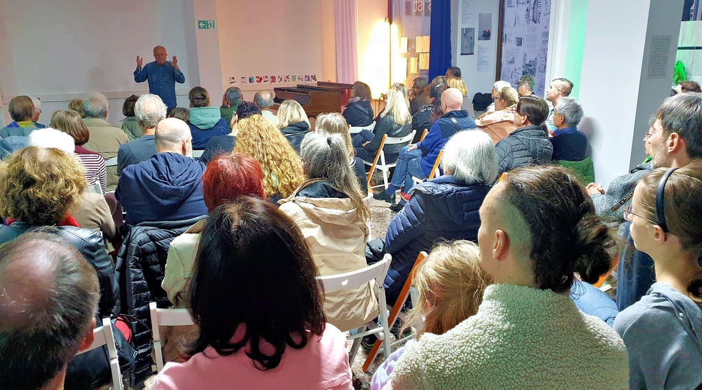 Der Künstler und Schirmherr Yadegar Assisi begrüßt die Kunstinteressierten im komplett gefüllten Stadtlabor.