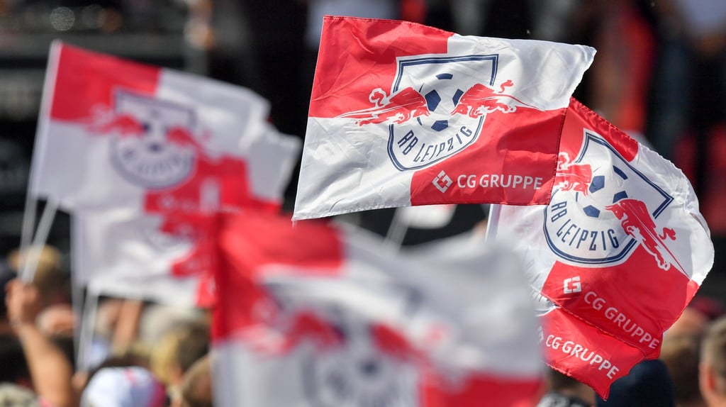 Fahnen mit dem Logo von RB Leipzig werden geschwenkt.