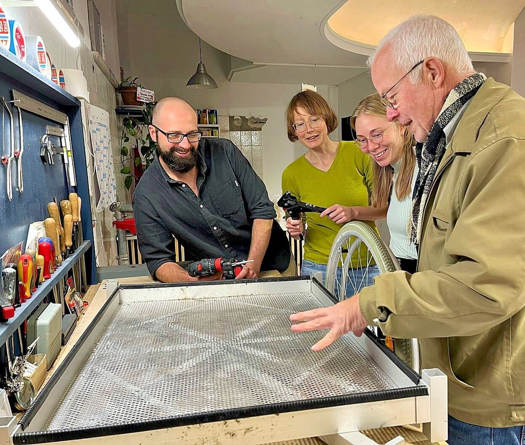 Felix Moosdorf (hinten im Bild) berät mit Mitstreitern die Reparatur eines Fahrradanhängers.