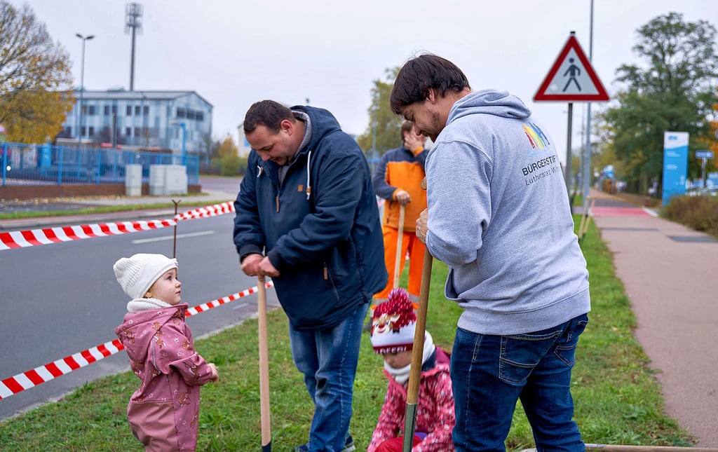 René Müller (re.), der Vorstandsvorsitzende der Bürgerstiftung, hat auf einer Grünfläche vor der Betriebs-Kita von SKW Piesteritz und Agrofert fleißige Helfer.