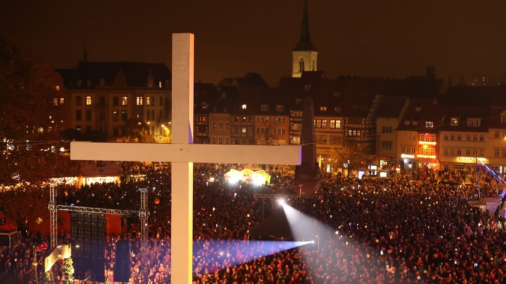 Teilnehmer beim ökumenischen Martinsfest schwenken ihre Laternen auf dem Erfurter Domplatz.
