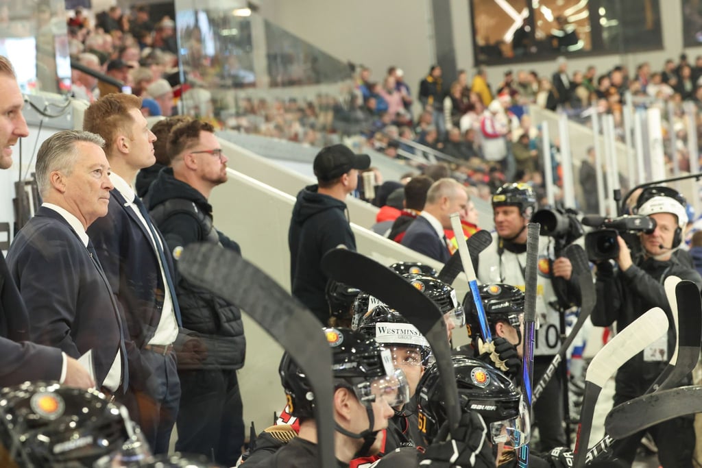 Bundestrainer Harold Kreis begrüßt Kameras in der Eishockey-Kabine.