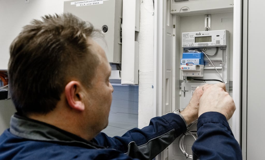Ein Elektriker montiert einen digitalen Stromzähler mit einem Smart-Meter-Gateway zur Datenübertragung.
