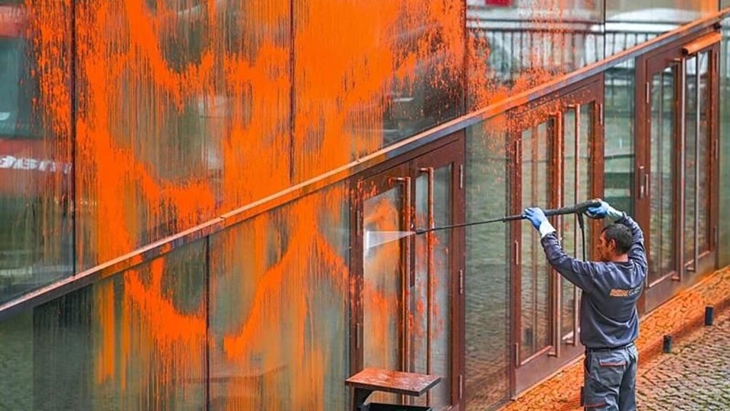 Ein Reinigungsmitarbeiter entfernt im Oktober 2023 die Reste der Farbattacke vom „Audimax“ an der Uni Halle.