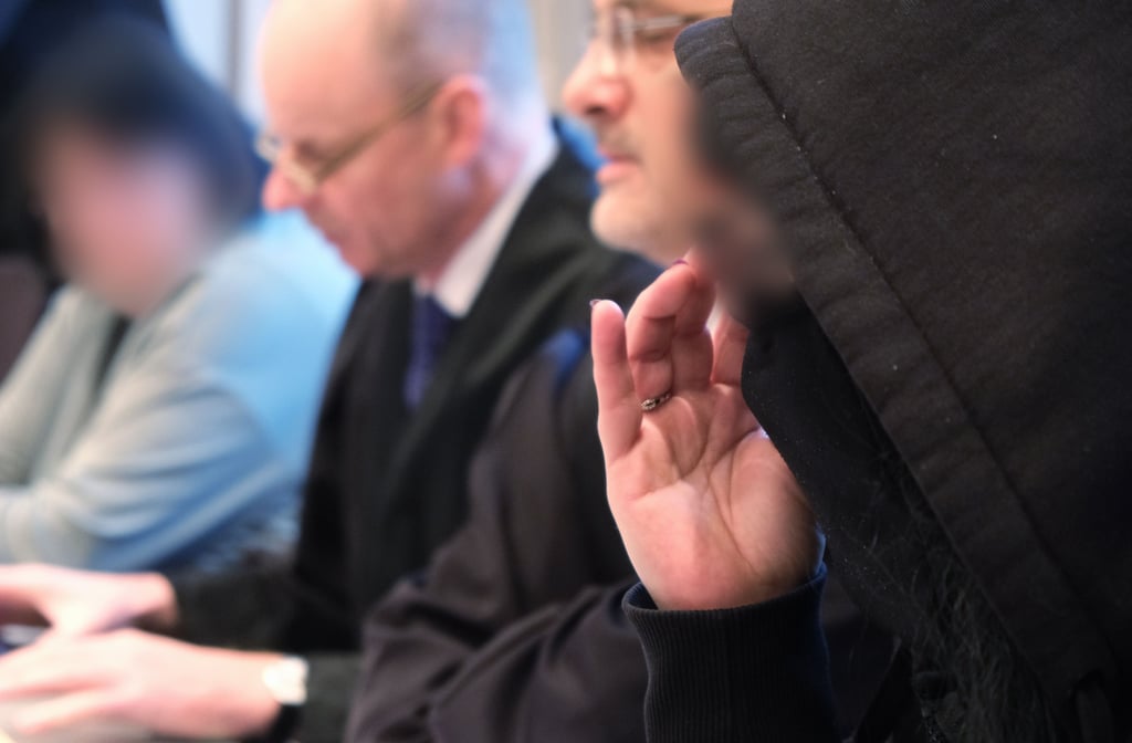 Zwei der Angeklagten (l. und r.) sitzen zum Prozess an ihren Plätzen in einem Saal des Landgerichts Halle.