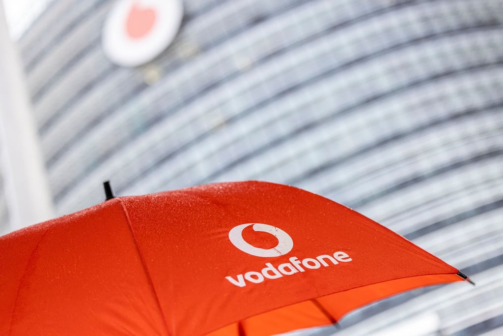 Ein Passant geht mit einem aufgespanntem Regenschirm mit dem Logo von Vodafone an der Zentrale der Deutschlandtochter des britischen Vodafone-Konzerns vorbei.