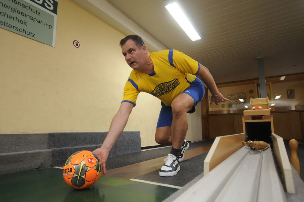 Ralf Staake "schiebt" einen Fußball in Richtung "Alle Neune".
