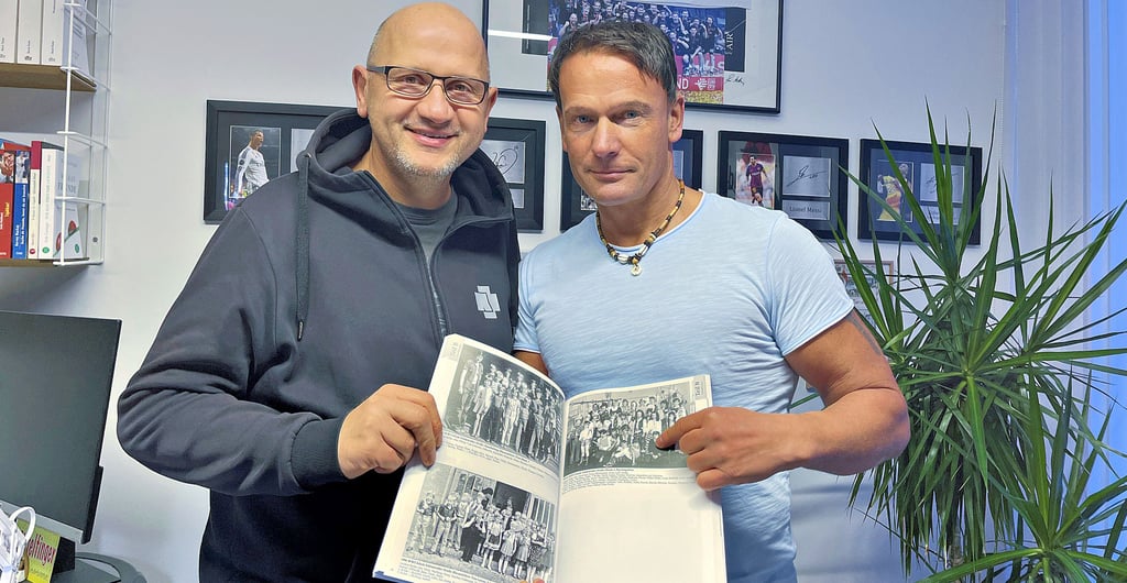 Hartmut Schulz (links) und Mark Wilke mit dem Buch „Tangerhütter Schulen“ von Albrecht Will, in dem auch ein Faschingsfoto ihrer Klasse aus den 80ern zu finden ist.