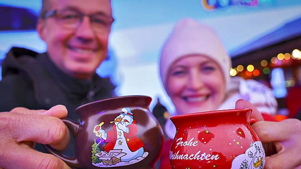Ein Paar stößt mit Glühweinbechern an.