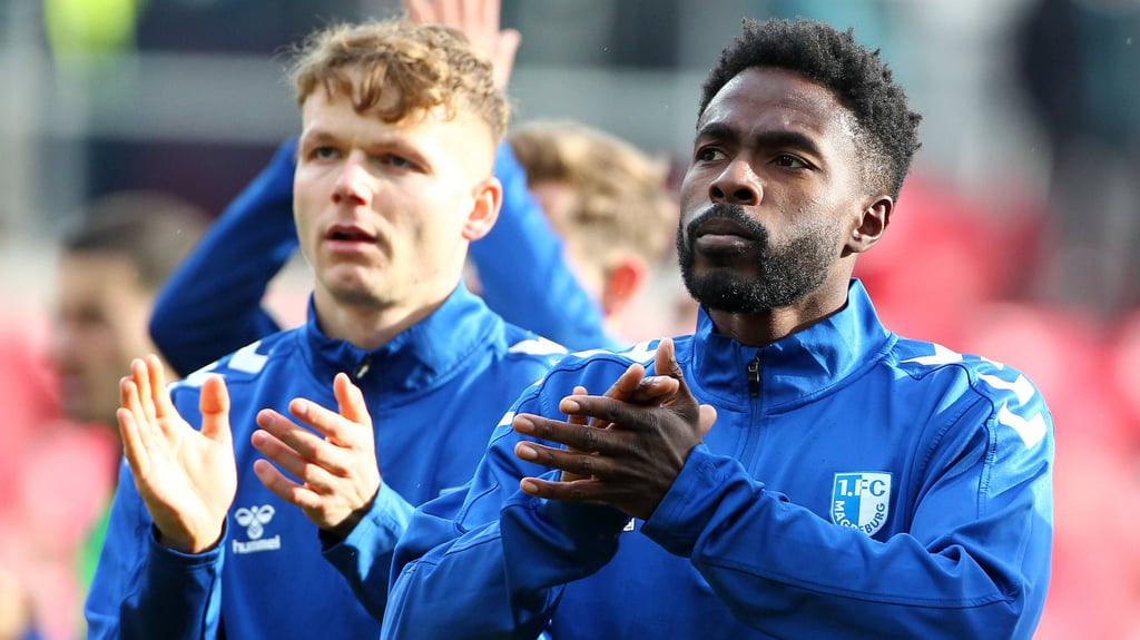 Philipp Hercher (li.) und Daniel Heber vom 1. FC Magdeburg feiern den Sieg gegen Jahn Regensburg mit den mitgereisten Fans im Jahnstadion.