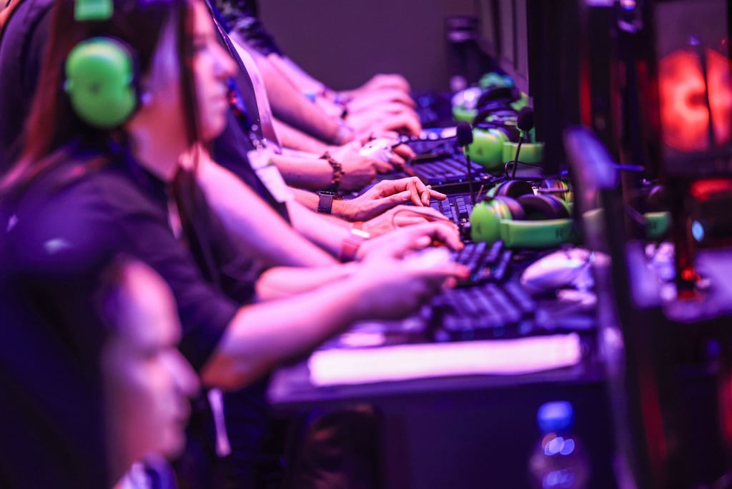 Computerspielerinnen und Computerspieler sitzen im August 2024 bei der Messe Gamescom vor Bildschirmen.
