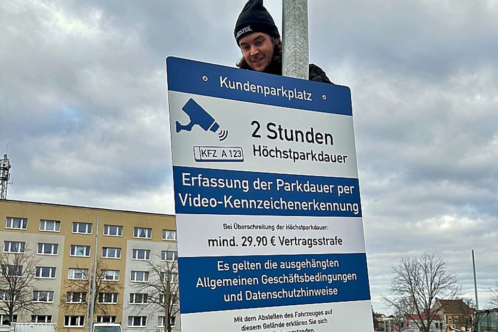 Noah Ronshausen befestigt die Park-Hinweisschilder auf dem neuen Edeka-Parkplatz in der Stadtmitte von Burg.