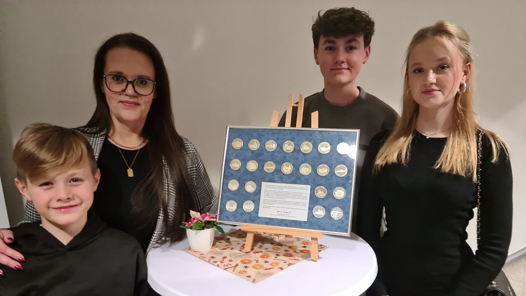 Sarah, Mia, Paul, und Till - Familie eines Havelberger Soldaten bei derVergabe der Anerkennungsmedaille 2024 vor den Medaillen-Motiven, die seit 2003 überreicht wurden.