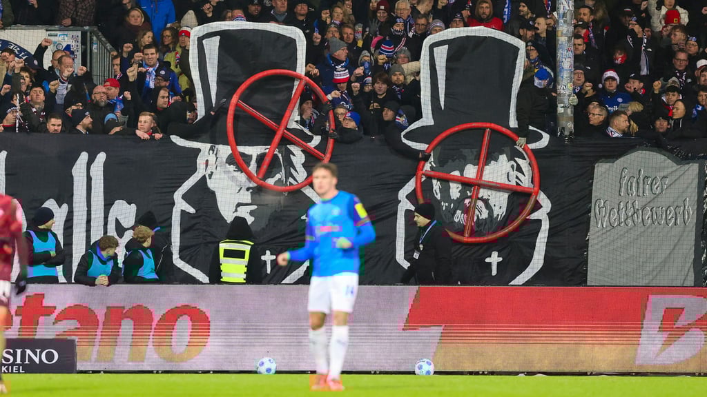 Banner im Kieler Fanblock zeigen die Gesichter von Oliver Mintzlaff und Jürgen Klopp mit einem Fadenkreuz darüber.