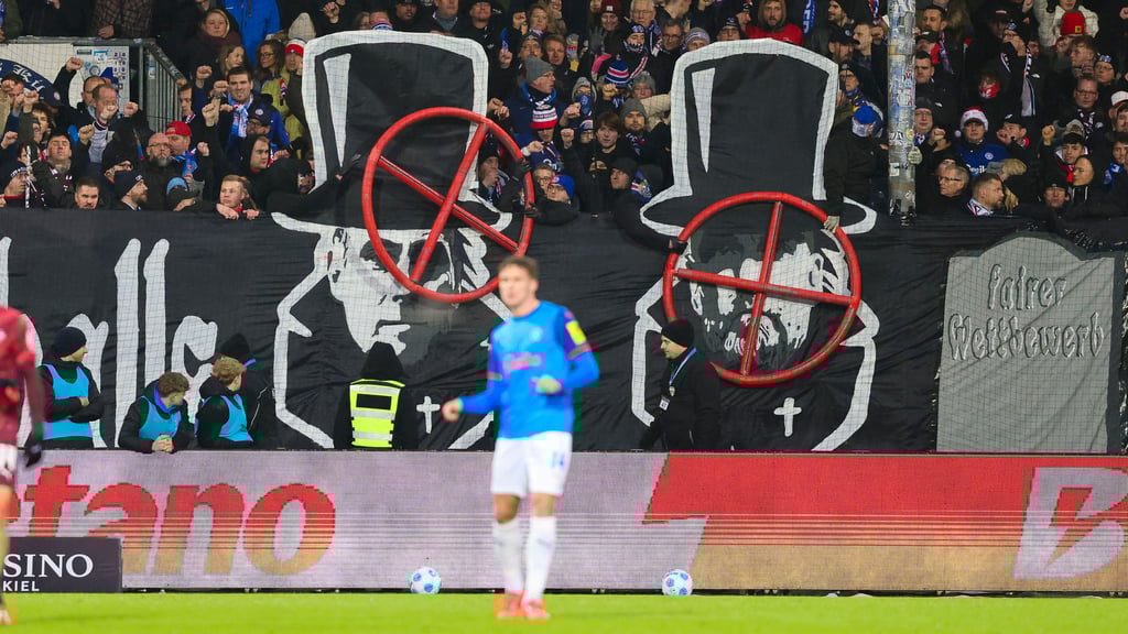 Banner im Kieler Fanblock zeigen die Gesichter von Oliver Mintzlaff und Jürgen Klopp mit einem Fadenkreuz darüber.