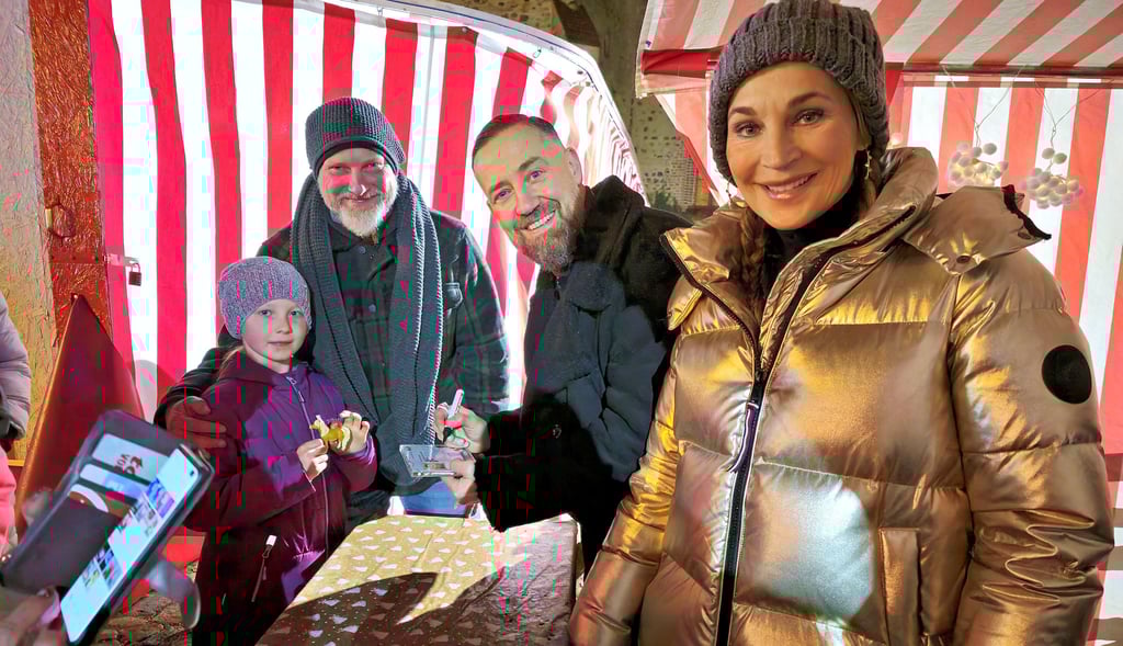 Bürger Lars Dietrich (2. v. r.) und Caroline Beil (r.) geben auf dem Zerbster Weihnachtsmarkt Autogramme.