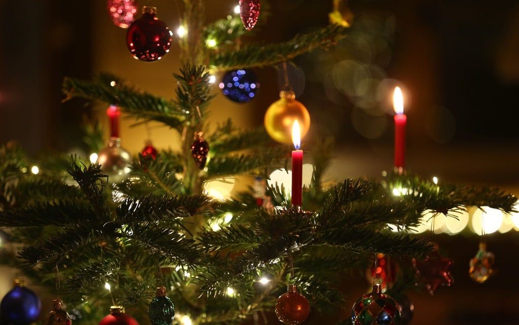 Kerzen brennen in einem Wohnzimmer an einem geschmückten Christbaum: heutzutage oft schon zeitiger im Dezember als früher. (Symbolbild)