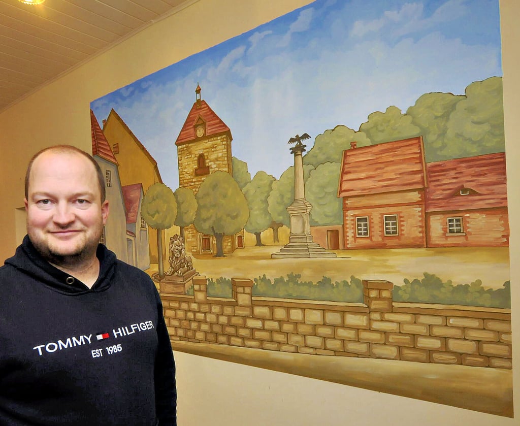 Gekommen, um zu bleiben: Der aus Niederholzhausen stammende Gastronom Sebastian Sieber (hier vor dem Wandbild mit historischer Marktansicht) baut sich in Nebra nun ein drittes geschäftliches Standbein auf.