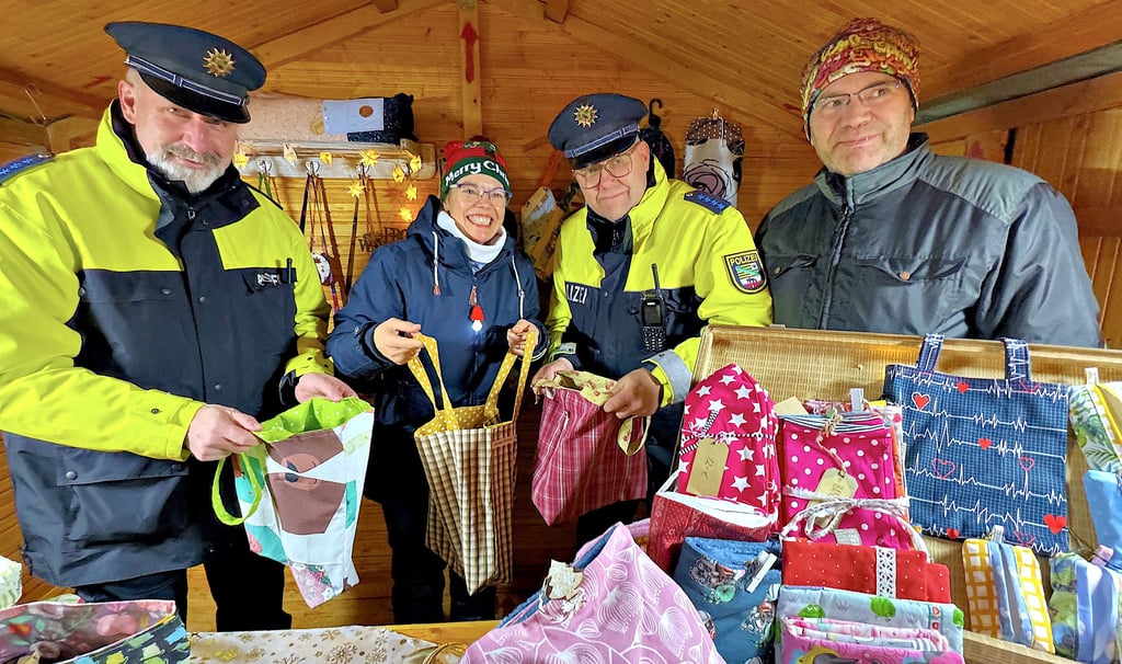 So macht eine Taschenkontrolle Spaß: Die Polizisten Alexander Polowniew und Sven Radschun (li,) begutachten auf dem Weihnachstmarkt Möckern die handgefertigten Taschen von Katja und Guido Kühntopp aus Gerwisch.