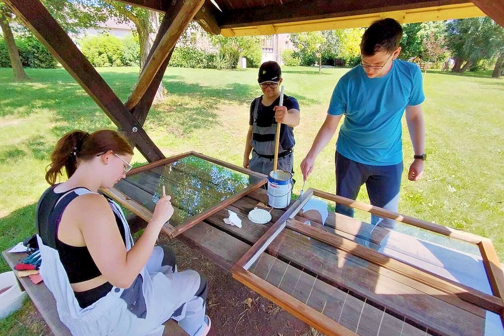 Bei der jüngsten Ferienfreizeit: Mitglieder der Jugendgruppe schleifen alte Holz-Fensterrahmen ab und streichen sie neu.
