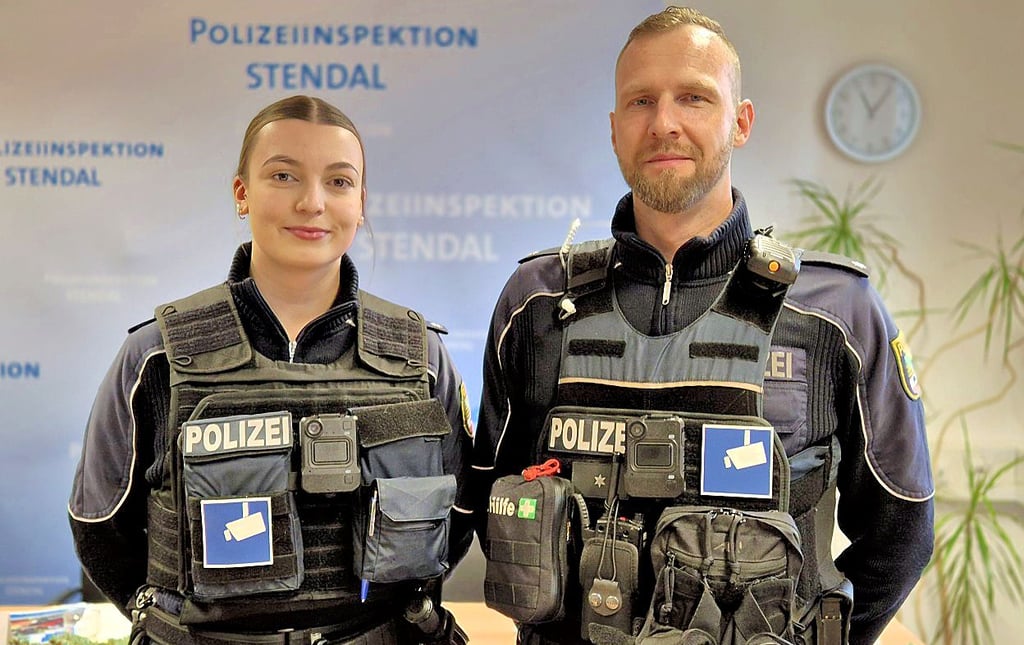 Die Stendaler Polizeikommissare Anna Finke und Thomas Boguslawski demonstrieren die Bodycams, die sich mittig neben dem Kamerasymbol am Körper befinden.