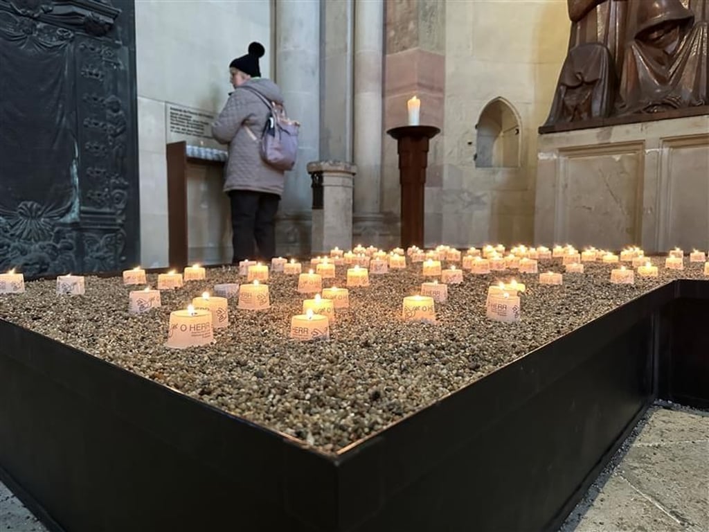 Im Dom werden Kerzen im Gedenken angezündet. Dutzende Menschen sind dort.