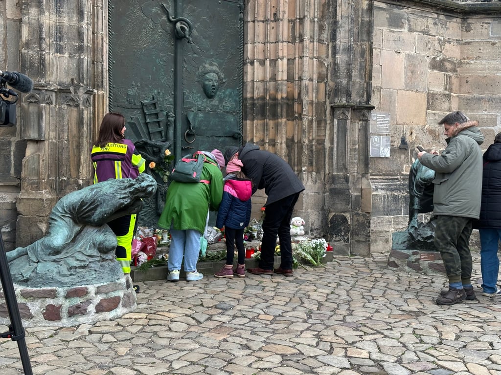 Menschen legen nach der Todesfahrt auf dem Magdeburger Weihnachtsmarkt Blumen vor die Johanniskirche.