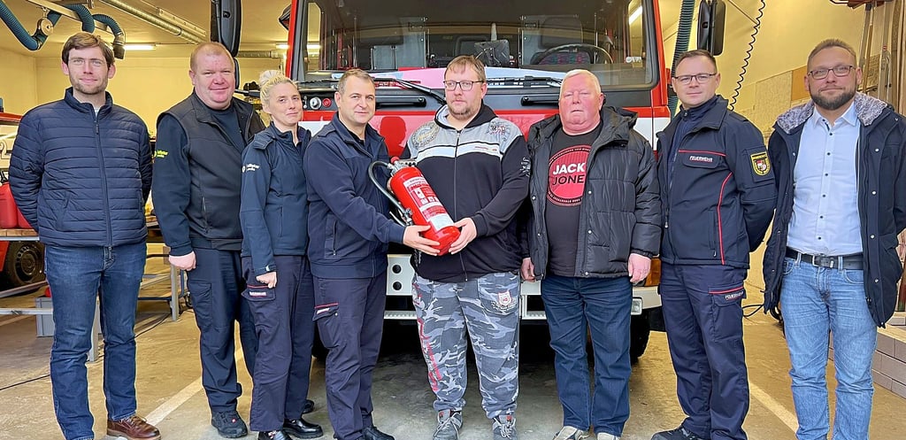 Enrico Zeugner (2.v.l.) übergibt mit seinen Kameraden den „Spenden-Feuerlöscher“ an Rebenstorf (5.v.l.).