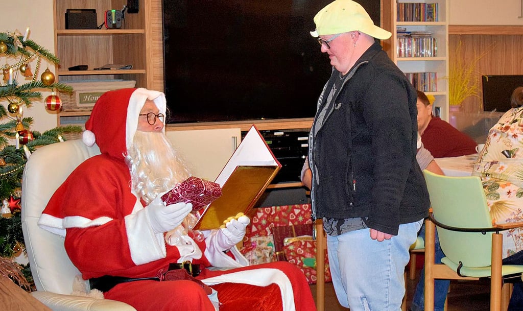 Der Weihnachtsmann verteilt die Geschenke an die Bewohner.