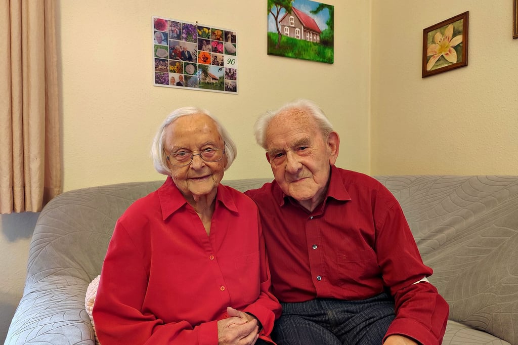 Hanna und Siegmund Bartsch, 92 und 94 Jahre alt, auf der Couch in ihrem Wohnzimmer. Am heutigen Silvestertag feiern sie das seltene Jubiläum der Gnadenhochzeit. Im Hintergrund: ein Bild (rechts), das das Geburtshaus von Hanna Bartsch in Ostpreußen zeigt, gemalt von ihrer Enkelin.