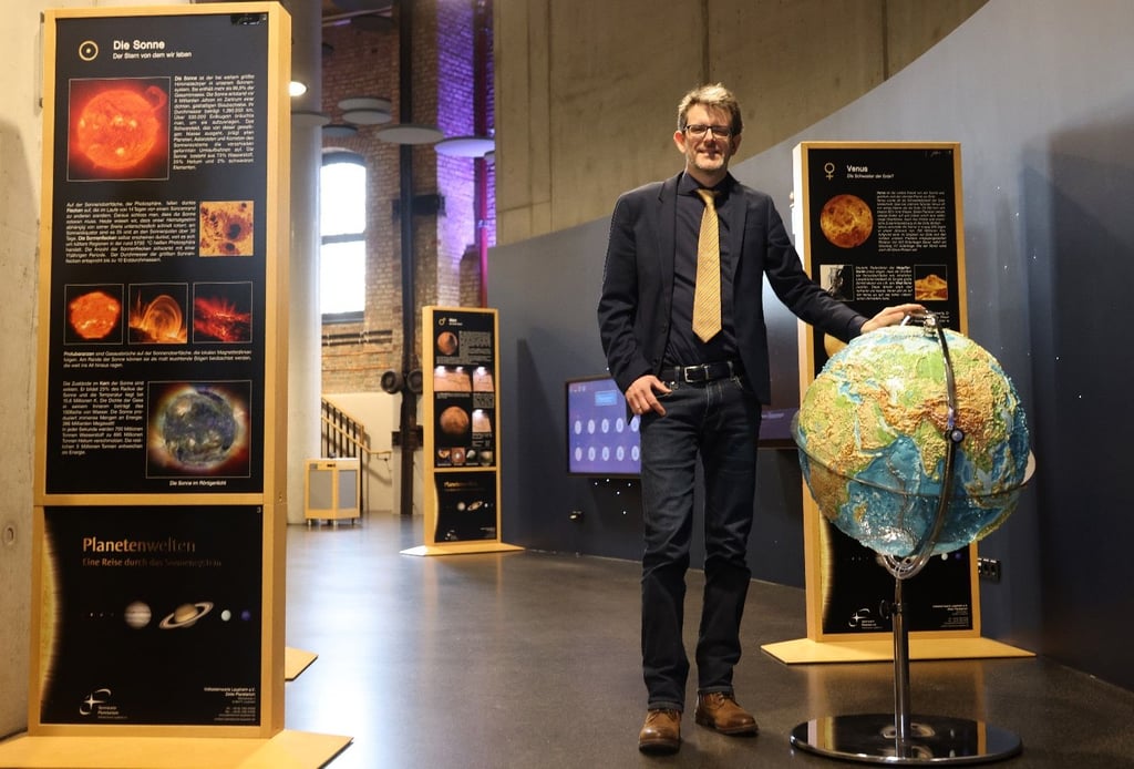 Planetariumschef Dirk Schlesier neben einem Erd-Globus mit reliefartiger Oberfläche zum Anfassen, der zur neuen Planeten-Ausstellung gehört