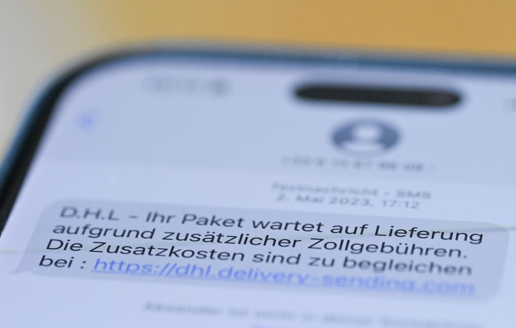 Auf einem Smartphone ist eine Betrugs-SMS zu lesen, in der Kriminelle ein Paket ankündigen und dafür Zollgebühren einfordern.