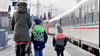 Eine Mutter mit ihren Kindern  im Winter  auf einem nicht überdachten  Bahnsteig.