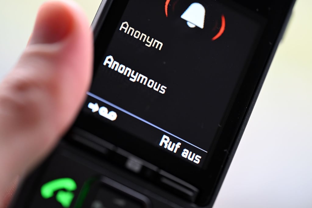 ILLUSTRATION - Ein Mann hält ein Festnetz-Telefon, auf dem ein anonymer Anruf eingeht (gestellte Szene).
