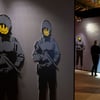 Chemnitz: Eine Besucherin steht in der Ausstellung "Banksy - A Vandal Turned Idol" in der Markthalle. Am Samstag wurde dort ein Kunstwerk gestohlen.