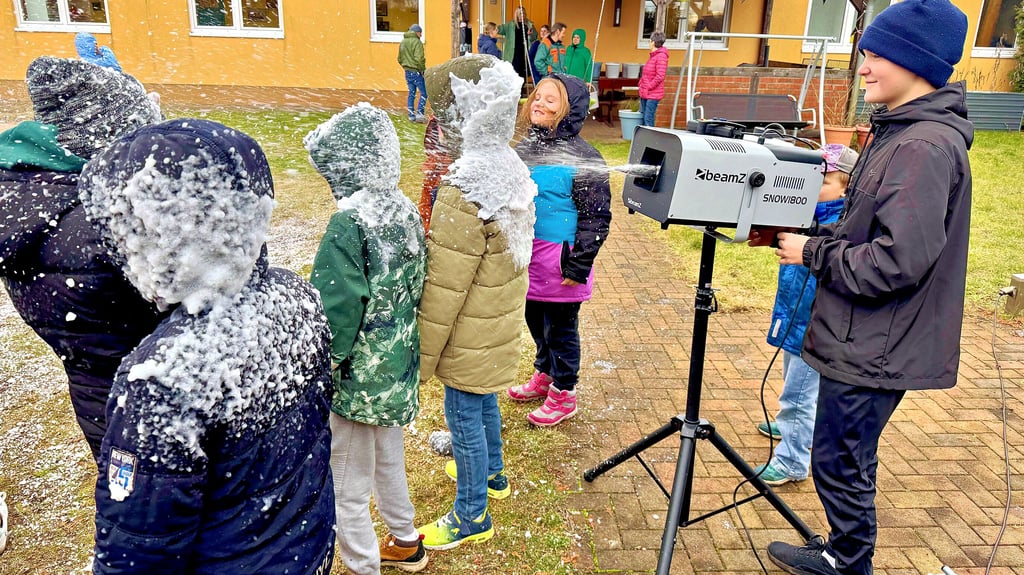 Ben Szczegula hat an der Schneekanone seinen Spaß. Die Kinder lassen den künstlichen Schnee auf ihre Jacken prasseln.