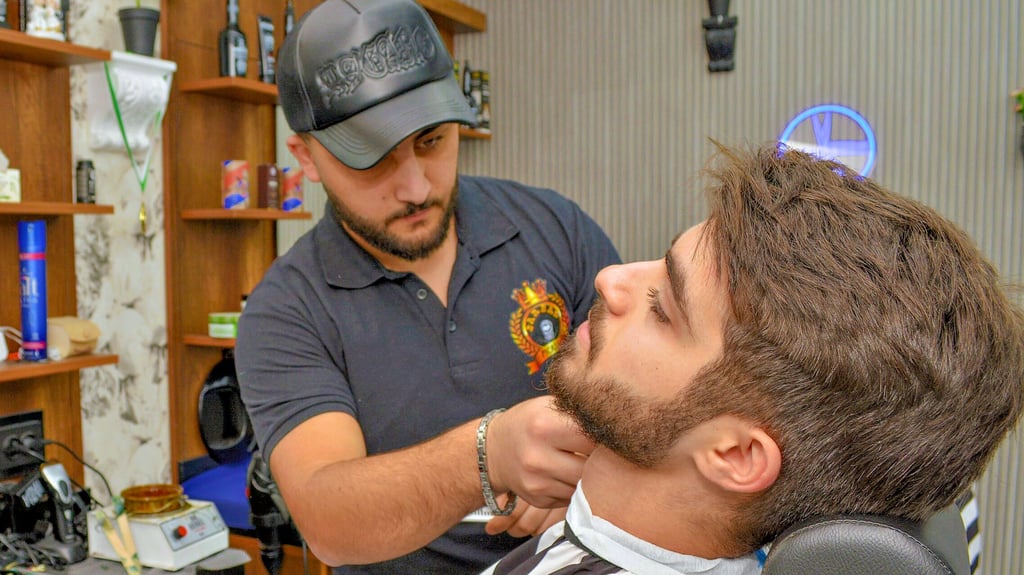 Barbier Dilo kümmert sich um den Bart von Jasin, einem guten Freund und Stammkunden im Picasso Barber-Shop in Wanzleben.
