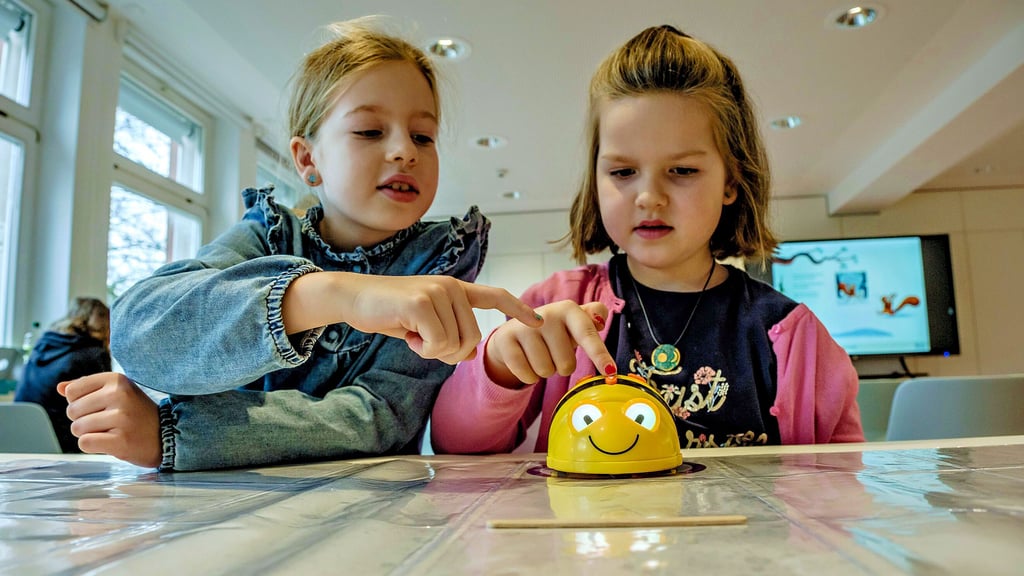Tessa und Mira lassen den Beebot auf der Unterlage umherfahren. Zuvor müssen sie ihn aber richtig programmieren.