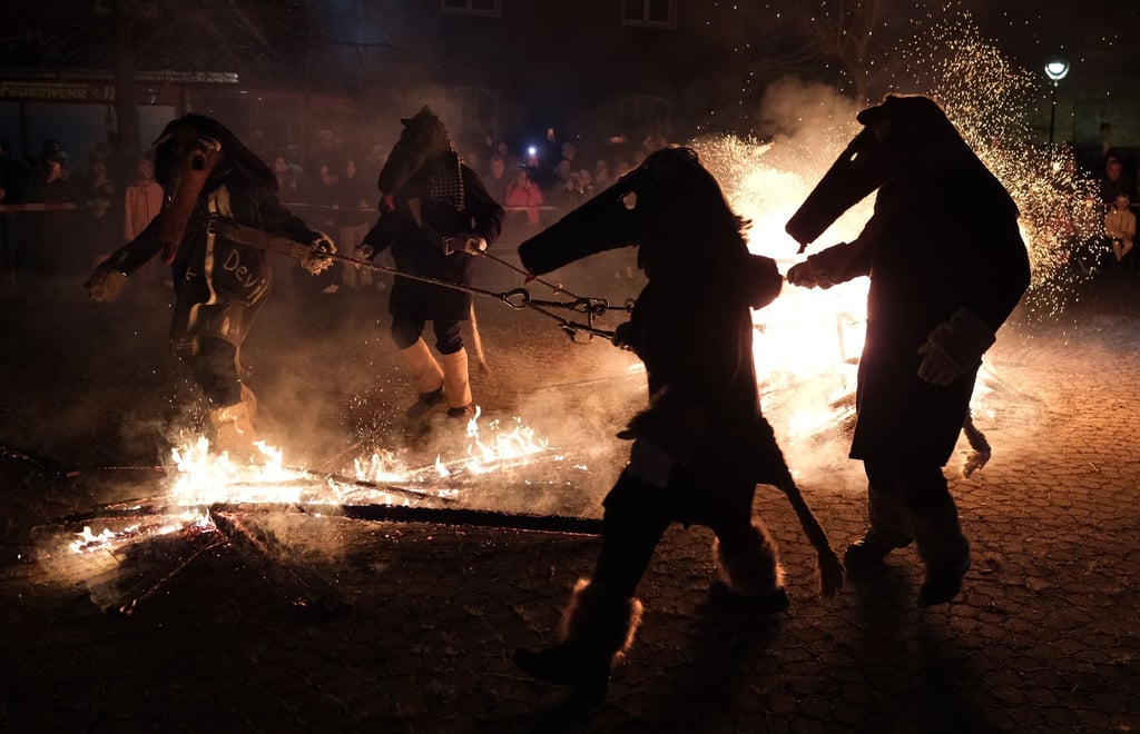 Als Pferde verkleidete Einwohner von Spergau brechen durch das Feuer.