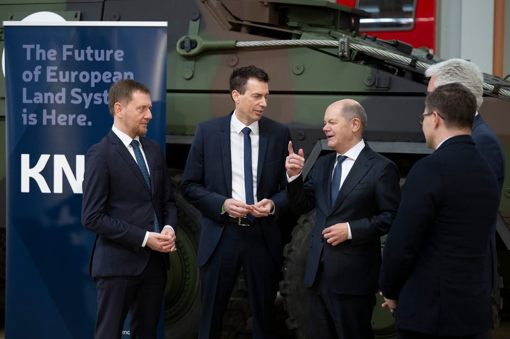 In einer Werkhalle von Alstom, zukünftig KNDS: Kanzler Olaf Scholz mit Sachsens Regierungschef Michael Kretschmer (links) und KNDS-Manager Florian Hohenwarter (Mitte).
