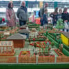 Besucher betrachten eine Kleingartensparte im Miniaturformat auf der Messe "Haus Garten Freizeit" auf dem Leipziger Messegelände.