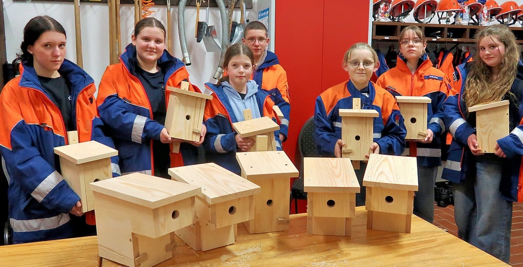 Mitglieder der Jugendfeuerwehr Warnau zeigen die Nistkästen, die in zwei verschiedenen Formen entstanden sind.