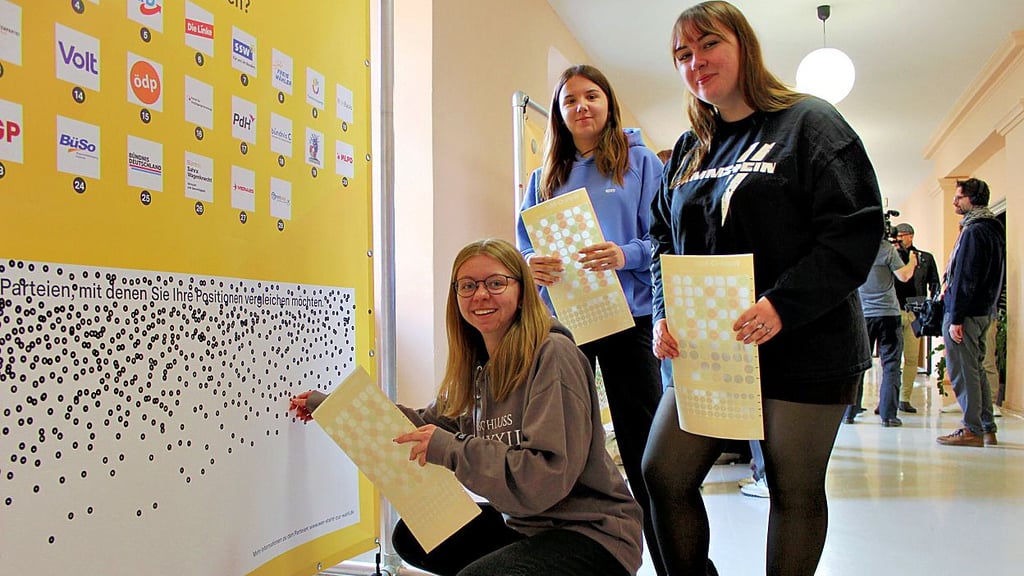 Mit Stickern kleben die angehenden Sozialassistentinnen Mathilda Wedler (hockend), Amélie Schröder und Maria Celine Sommer ihr Ergebnis des analogen Wahl-O-Maten an die Tafel.