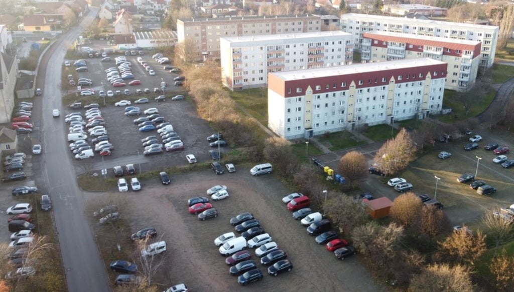 Auf drei großen Flächen und entlang der Straße, hier auf diesem älteren Foto zu sehen, parken vor allem die Mitarbeiter aus dem Industriepark. Den Block im Hintergrund gibt es nicht mehr; dafür wurde der Park der Generationen angelegt.